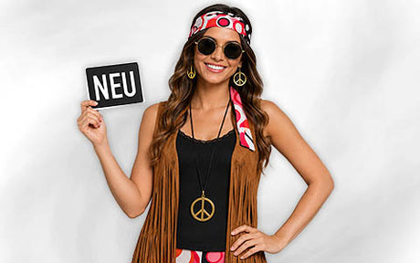 Eine Frau in einem Retro-Hippie-Kostüm mit Accessoires mit Peace-Zeichen, die ein Schild mit der Aufschrift „NEU“ in der Hand hält und vor einem einfarbigen Hintergrund steht.