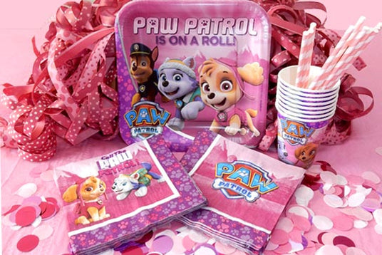 Partyzubehör zum Thema „Paw Patrol“, darunter Teller, Servietten, Becher, Strohhalme und rosa Dekorationen, die auf einem Tisch angeordnet sind.
