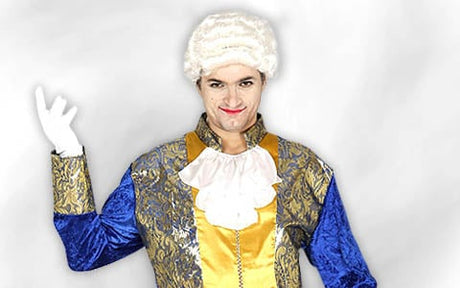 Eine Person in einem Kostüm im Stil des 18. Jahrhunderts mit weißer Perücke, Rüschenkragen, blau-goldener Jacke und weißen Handschuhen, die mit erhobener Hand posiert.