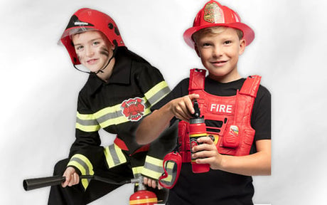Zwei Kinder in Feuerwehrkostümen, von denen eines einen Spielzeug-Feuerlöscher und das andere einen Spielzeug-Feuerwehrschlauch in der Hand hält; beide tragen rote Helme und lächeln.