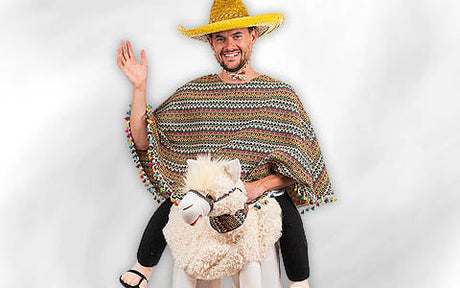 Ein Mann, der einen Strohsombrero und einen bunten Poncho trägt, winkt, während er auf einem weißen Lama-Kostüm sitzt.