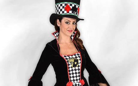 Eine Frau in einem vom verrückten Hutmacher inspirierten Kostüm mit kariertem Muster, einem hohen Hut und roten Akzenten, die vor einem einfarbigen Hintergrund steht.