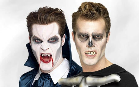 Zwei Personen in Halloween-Kostümen: Die eine ist als Vampir mit Reißzähnen und Blut verkleidet, die andere als Skelett mit aufgemaltem Totenkopf-Make-up und künstlichen Zähnen; beide blicken in die Kamera.