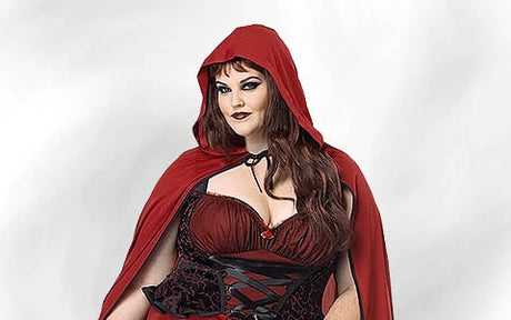 Eine Person, die einen roten Umhang mit Kapuze und ein dunkelrotes Korsettkleid trägt und vor einem schlichten, hellen Hintergrund steht.