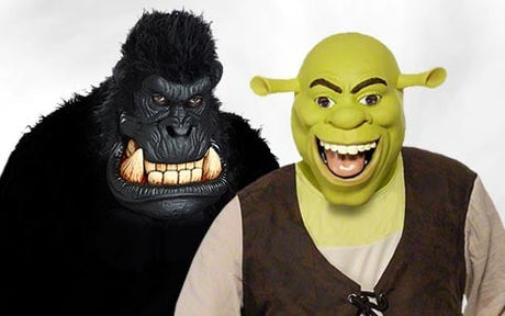 Zwei Personen in Kostümen: eine als schwarzer Gorilla mit gefletschten Zähnen und die andere als Shrek mit grünem Gesicht, großen Ohren und einem breiten Lächeln, die vor einem schlichten Hintergrund stehen.