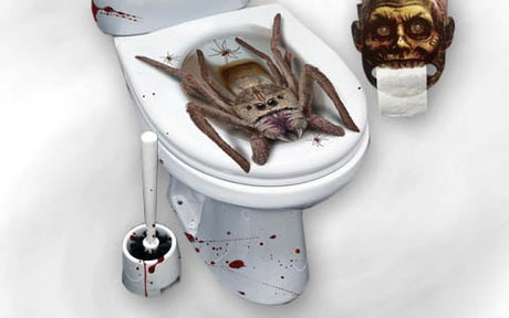 Eine große künstliche Spinne sitzt auf einem Toilettensitz mit künstlichen Blutspritzern; daneben liegen eine Toilettenbürste und ein Toilettenpapierhalter im Zombie-Design.