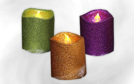 Drei glitzernde LED-Kerzen in den Farben Grün, Gold und Lila mit künstlichen Flammen vor einem weißen Hintergrund.