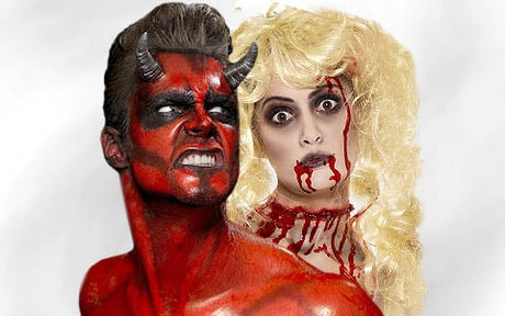Ein Mann mit roter Haut, Hörnern und scharfen Zähnen posiert vor einer Frau mit blonden Haaren, dunklen Augen und Kunstblut an Mund und Hals.