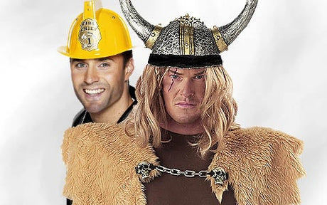 Ein lächelnder Mann mit einem gelben Feuerwehrhelm steht hinter einem anderen Mann, der als Wikinger mit einem gehörnten Helm und einem Pelzanzug verkleidet ist.