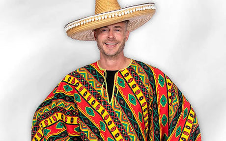 Ein Mann, der einen großen Strohsombrero und einen bunt gemusterten Poncho trägt, steht lächelnd vor einem schlichten weißen Hintergrund.