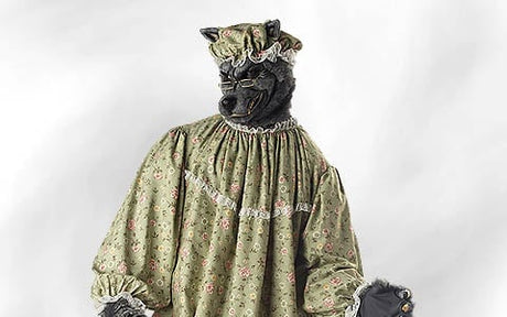 Eine Person mit einer Wolfsmaske und einer Brille trägt ein grünes Nachthemd mit Blumenmuster und eine Mütze, was auf die Wolfsverkleidung aus „Rotkäppchen“ anspielt.