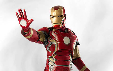 Eine Person in einem Iron-Man-Kostüm steht mit einem erhobenen Arm und nach vorne gerichteter Handfläche vor einem schlichten, hellen Hintergrund.