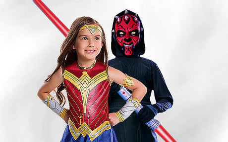 Ein Kind in einem Wonder-Woman-Kostüm steht vor einem anderen Kind, das als Darth Maul verkleidet ist und ein rotes Lichtschwert mit zwei Klingen in der Hand hält.