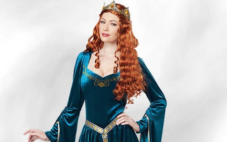 Eine Frau mit einer langen, lockigen roten Perücke, einer goldenen Krone und einem blaugrünen Kleid im mittelalterlichen Stil mit goldenen Verzierungen, die vor einem hellen Hintergrund steht.