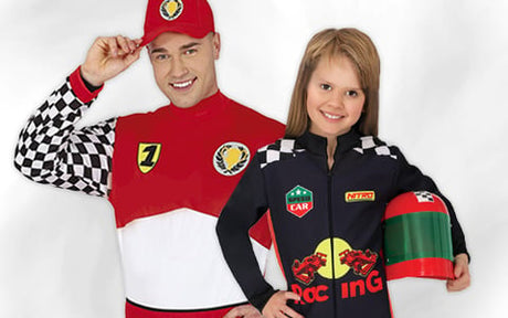 Ein Erwachsener und ein Kind in Rennfahrer-Kostümen; das Kind hält einen Spielzeug-Rennhelm in der Hand.