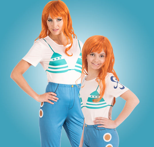 Zwei Personen mit langen orangefarbenen Perücken tragen aufeinander abgestimmte Outfits: weiße T-Shirts mit türkisfarbenen Motiven und blaue Hosen mit kreisförmigen Mustern; sie stehen vor einem blauen Hintergrund.