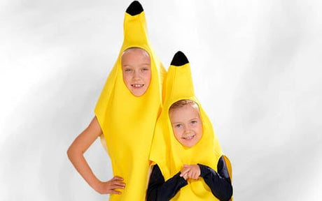 Zwei Kinder in gelben Bananenkostümen stehen vor einem schlichten, hellen Hintergrund und lächeln in die Kamera.