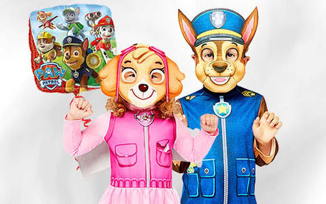 Zwei Personen in Kostümen der „Paw Patrol“-Figuren, eine in Rosa und eine in Blau, posieren gemeinsam vor einem einfarbigen Hintergrund und halten einen Ballon mit „Paw Patrol“-Motiv in der Hand.