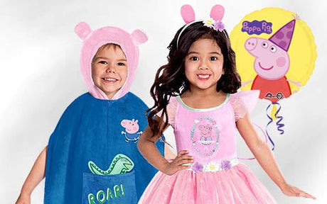 Zwei Kinder tragen Kostüme mit Peppa-Pig-Motiven – das eine einen blauen Poncho mit Schweinekappe, das andere ein rosa Kleid mit Mausohren – und stehen vor einem Peppa-Pig-Ballon.