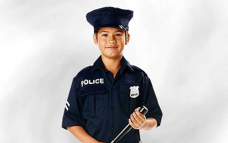 Ein Kind in einer dunkelblauen Polizeiuniform und mit einer Polizeimütze hält einen Schlagstock in der Hand und steht vor einem schlichten weißen Hintergrund.