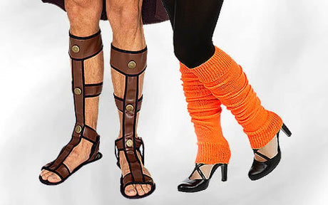 Zwei Personen stehen da; die eine trägt braune Gladiatorensandalen mit Schienbeinschonern, die andere schwarze Pumps mit leuchtend orangefarbenen Stulpen.