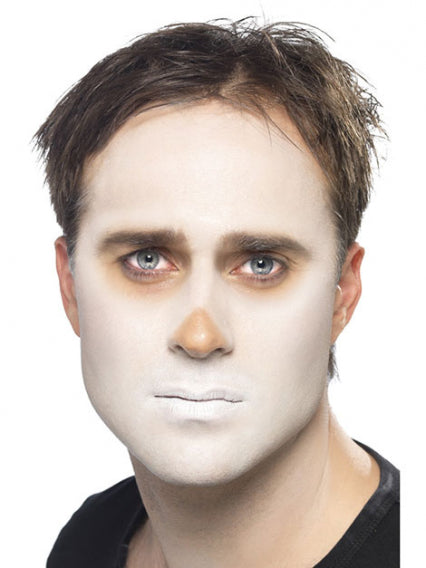 Ein Mann mit kurzen braunen Haaren, dessen Gesicht weiß bemalt ist und um Nase und Augen herum braune Schattierungen aufweist; er trägt ein schwarzes Hemd und blickt vor einem weißen Hintergrund direkt in die Kamera.