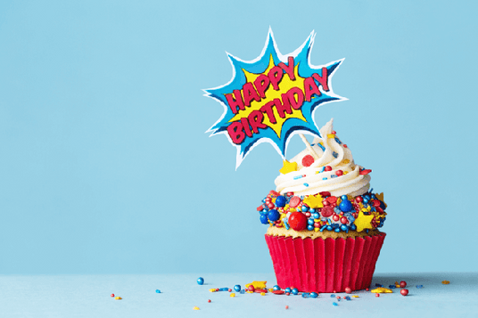 Ein Cupcake mit bunten Streuseln und der Aufschrift „Happy Birthday“ im Comic-Stil vor einem einfarbigen blauen Hintergrund.