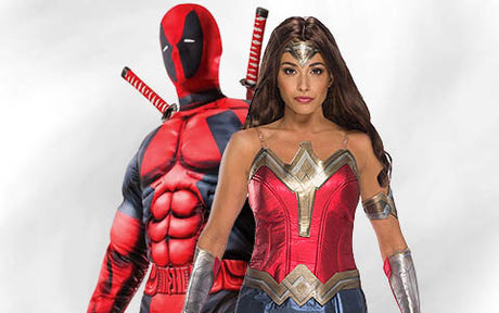 Zwei kostümierte Personen – die eine als Deadpool in einem rot-schwarzen Anzug und mit Schwertern, die andere als Wonder Woman in einem rot-gold-blauen Outfit und mit einer Tiara – stehen vor einem schlichten Hintergrund.