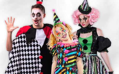 Drei Personen in bunten Clownskostümen und mit Clown-Make-up posieren gemeinsam vor einem weißen Hintergrund.