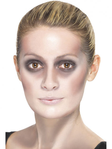 Eine Frau mit nach hinten geglätteten Haaren hat blasse Haut und dunkle Ringe um die Augen, was ihr ein müdes oder dramatisches Aussehen verleiht.