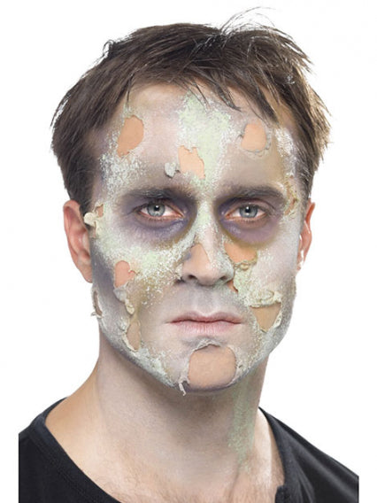 Ein Mann mit realistischem Zombie-Make-up, gekennzeichnet durch blasse Haut, dunkle Augenringe und Effekte von abblätternder, verfaulter Haut.