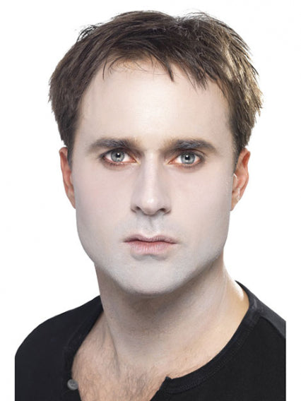 Ein Mann mit blasser Haut, dunklem Haar und hellen Augen blickt direkt in die Kamera. Er trägt ein schwarzes Hemd und wirkt vor dem weißen Hintergrund ausdruckslos.