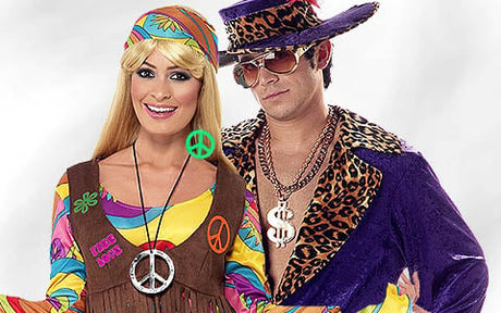 Zwei Erwachsene in bunten Kostümen; einer in einem Hippie-Outfit mit Peace-Zeichen, der andere mit einem auffälligen Hut, einer Sonnenbrille und einer Jacke mit Leopardenmuster sowie einer großen Halskette mit Dollarzeichen.